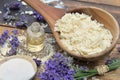 Spoon full of flakes of soap with essential oil and lavender flowers and sodium bicarbonate on wooden background Royalty Free Stock Photo