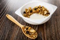 Spoon with granola, cereal breakfast with peanut, raisin and yogurt in bowl, on wooden table