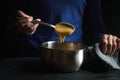 Spoon in hand with base sauce roux on blue background side view Royalty Free Stock Photo