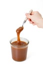 Spoon in hand with salty caramel and a jar Royalty Free Stock Photo