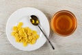 Spoon with honey in plate with corn flakes, bowl with honey on wooden table. Top view
