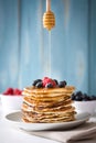 Spoon honey pouring honey on pancake