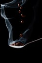 Spoon with hot coffee beans with smoke on a black background with falling coffee beans Royalty Free Stock Photo