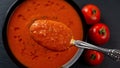 Spoon of hot tomato soup over bowl closeup. Eating vegetable dish of pureed roasted tomatoes, garlic and basil. Healthy vegetarian Royalty Free Stock Photo