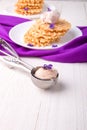 Spoon with ice cream. Belgian waffle on white plate decorated with purple flower. Royalty Free Stock Photo