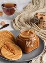 Spoon in a jar with homemade caramel sauce on the table. Close-up. Round caramel poured wafers in the foreground. Selective Focus Royalty Free Stock Photo