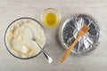 Spoon, margarine, flour, milk in bowl, oil in bowl, silicone pastry brush in mold on wooden table. Top view Royalty Free Stock Photo