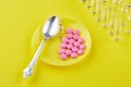 Spoon and pink tablets on saucer, ampoules on yellow background