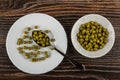 Spoon in plate with green peas, glass bowl with green peas on wooden table. Top view Royalty Free Stock Photo