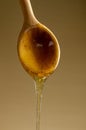 Spoon with a pouring drop of golden honey on yellow background Royalty Free Stock Photo