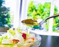 Spoon with pouring olive oil on italian fresh salad