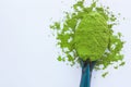 A spoon with powdered matcha green tea, isolated on light background, copy space, top view