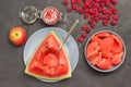 Spoon in pulp of ripe watermelon. Pieces of watermelon in gray bowl. Watermelon juice in glass jar. Apple and raspberry on table Royalty Free Stock Photo