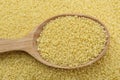 Spoon with raw couscous as background, top view