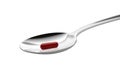 Spoon with red capsule isolated on white background. Closeup.