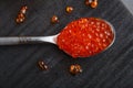 Spoon with red caviar on a black wooden background. Royalty Free Stock Photo