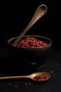 Spoon with red seeds in the black cup on a dark table, in the style of traditional vietnamese