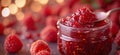 Raspberry jam. Spoon scooping homemade raspberry jam from a glass jar surrounded by fresh raspberries Royalty Free Stock Photo