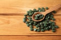 Spoon with spirulina tablets on wooden table Royalty Free Stock Photo