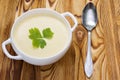 A spoon and tasty potato soup with a leaf of parsley, rustic wooden table. Potato and onion vegan, vegetarian healthy cream soup i