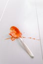 Spoon with tomato sauce splash on white table Royalty Free Stock Photo