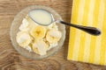 Spoon in bowl with cottage cheese, slices of banana and condensed milk, napkin on wooden table. Top view Royalty Free Stock Photo