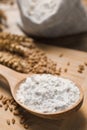 Spoon with wheat flour and grains on wooden board, closeup Royalty Free Stock Photo