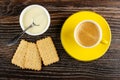Spoon in white bowl with condensed milk, dry cookies, black coffee in cup on saucer on wooden table. Top view Royalty Free Stock Photo