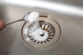 Baking soda in a spoon over a dirty dishwasher sink