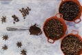Spoonful of coffee and pots of coffee beans and anise seeds on white surface