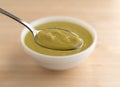 Spoonful of green pea soup with bowl in the background