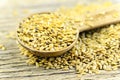 Spoonful of golden flax seed on wood background.