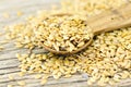 Spoonful of golden flax seed on wood background.