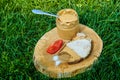 Spoonful of peanut butter on wooden plate with meat sandwich