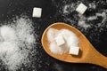 A spoonful of sugar in granules and cubes on a black background. Refined sugar, top view Royalty Free Stock Photo