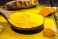 Spoonful of turmeric powder, turmeric roots in a wooden bowl Royalty Free Stock Photo