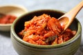 spooning spicy red kimchi onto plain rice bowl