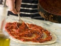 Spooning Tomato sauce onto a Pizza Base