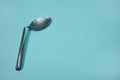 A used and bent spoon, isolated on a blue background.