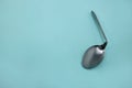 A used and bent spoon, isolated on a blue background.