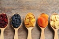 Spoons of different dried fruits on wooden background, top view with space for text Royalty Free Stock Photo