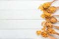 Spoons with different types of raw pasta on white wooden table Royalty Free Stock Photo