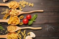 Spoons with different types of raw pasta on wooden background Royalty Free Stock Photo