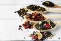 Spoons with dried herbal tea leaves and fruits on white wooden table, closeup. Space for text Royalty Free Stock Photo