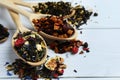 Spoons with dried herbal tea leaves and fruits on white wooden table, closeup. Space for text Royalty Free Stock Photo