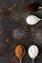 Spoons with icing sugar, green tea, coffee and cocoa on black background sprinkled with sugar, coffee, cocoa powder