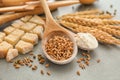 Spoons with wheat grains, flour and cut bread on table Royalty Free Stock Photo