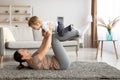 Sport activities with baby. Young mother exercising with her toddler son, balancing kid on knees, training on carpet Royalty Free Stock Photo