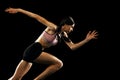 Studio shot of young muscular woman running isolated on black background. Sport, track-and-field athletics, competition Royalty Free Stock Photo