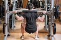 Sport, bodybuilding, lifestyle and people concept - young man with barbell doing squats in gym.